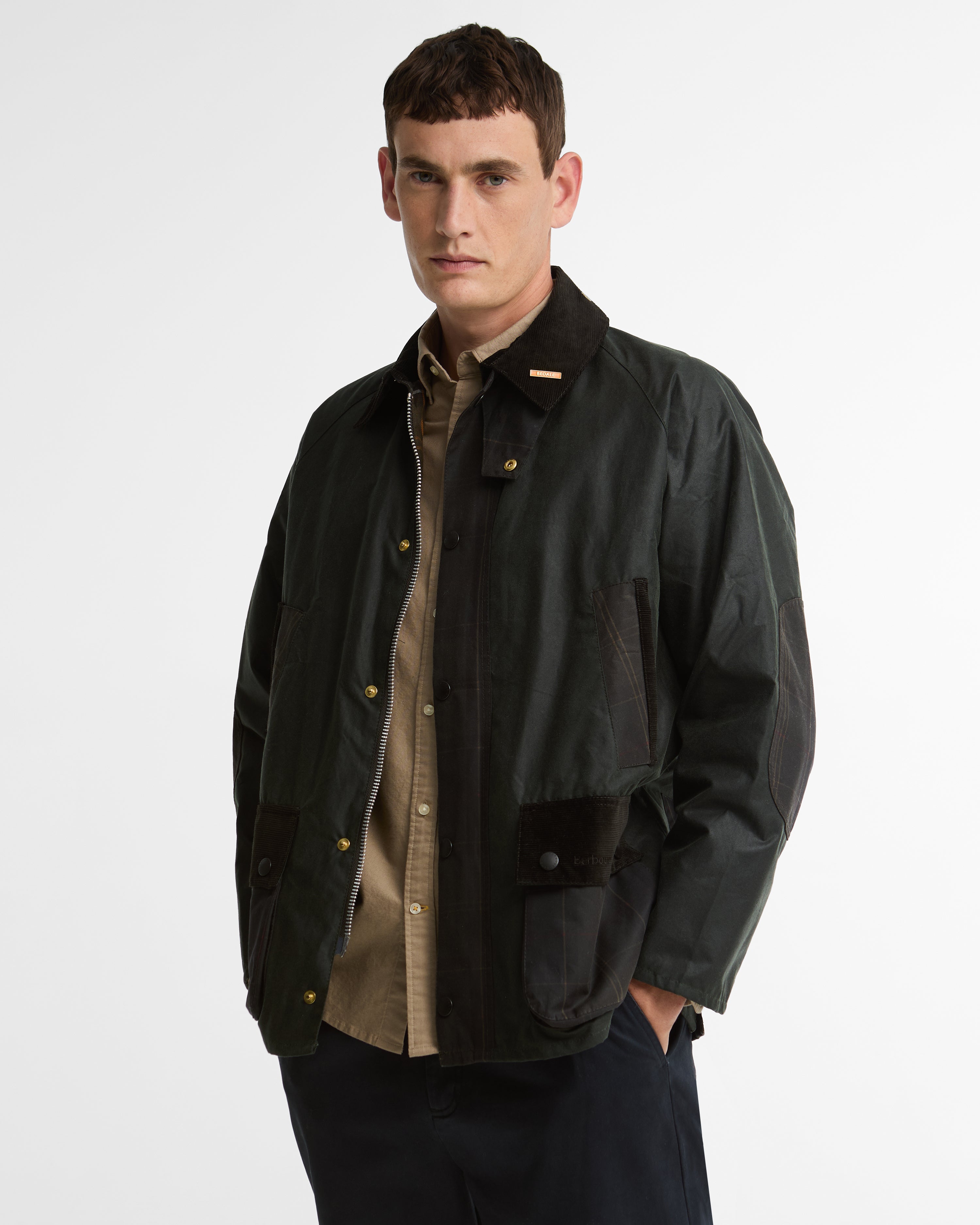 Model wearing the Barbour Icons Patch Bedale Wax Jacket, open in the front, showing the corduroy collar with Bedale pin and a gold snap button.