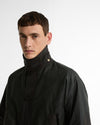 Close-up of a model wearing the Barbour Icons Patch Bedale Wax Jacket, showing the storm collar fastened with a gold snap button.