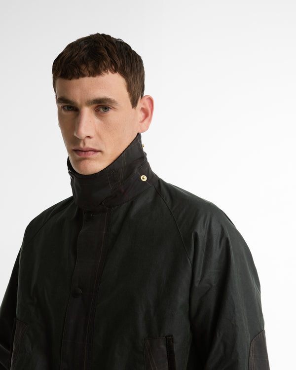 Close-up of a model wearing the Barbour Icons Patch Bedale Wax Jacket, showing the storm collar fastened with a gold snap button.