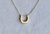 The Petite Horseshoe Necklace shown in 14k yellow gold.