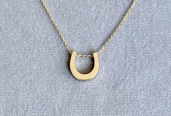 The Petite Horseshoe Necklace shown in 14k yellow gold.