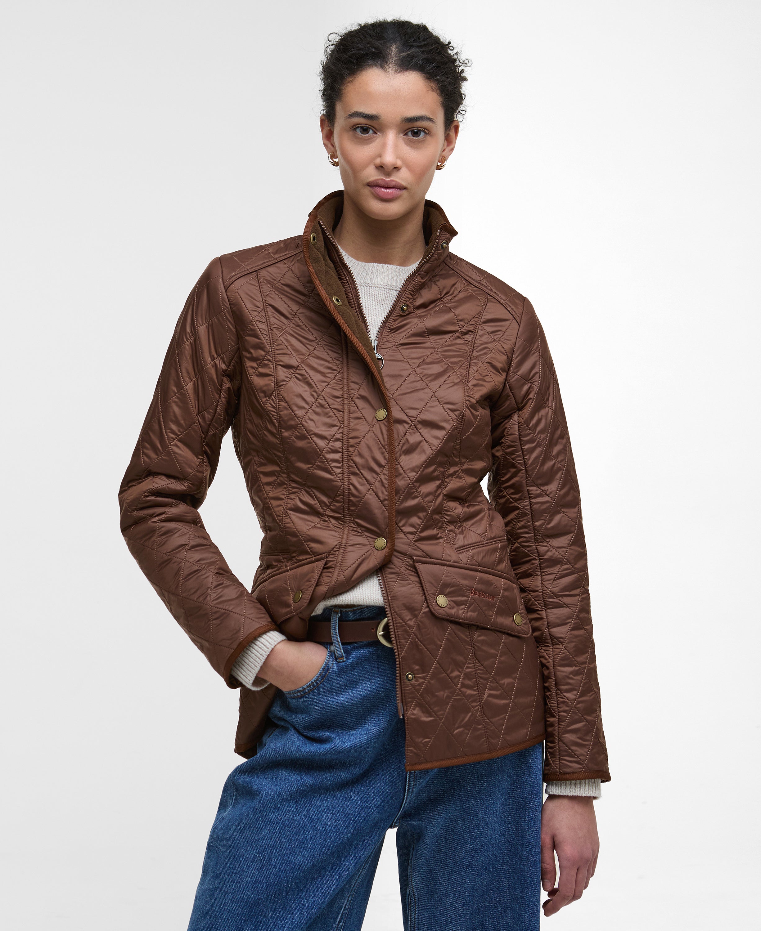 Person wearing a brown quilted jacket with a plain background