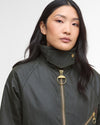 Woman wearing a dark green jacket with a gold zipper on a white background