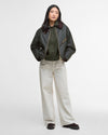 Person wearing a dark green jacket and light-colored pants on a white background
